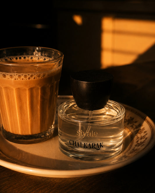 Siyate Chai Karak Eau de Parfum bottle beside a glass of traditional karak tea in warm afternoon light.