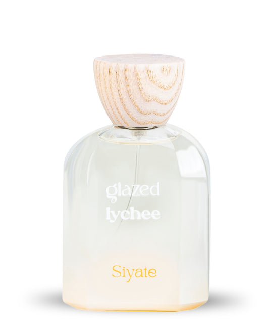 A clear glass perfume bottle with a light wood cap, labeled 'glazed lychee' and 'Siyate', on a white background.
