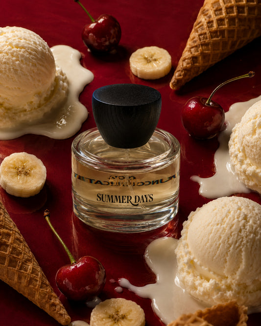 A bottle of siyate 'Summer Days' perfume centered on a rich red background, surrounded by melting vanilla ice cream, cherries, banana slices, and waffle cones.