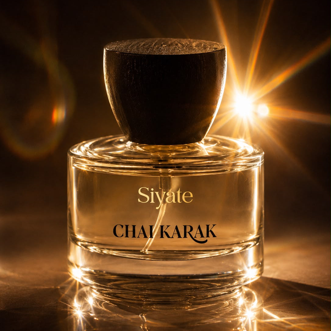 A bottle of Chai Karak fragrance by Siyate, featuring a clear glass bottle with a dark brown wooden cap, set against a dark background with dramatic golden light flares.