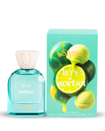 A bottle of lime sorbet eau de parfum next to its retail box. The bottle is made of translucent aqua glass with a light wood cap, and the box features illustrations of green lime slices and whole limes dripping with yellow lime juice.
