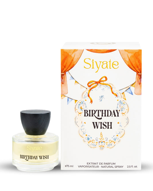 Siyate Birthday Wish perfume bottle with a black cap next to its white packaging box decorated with orange curtains and a gold bow.