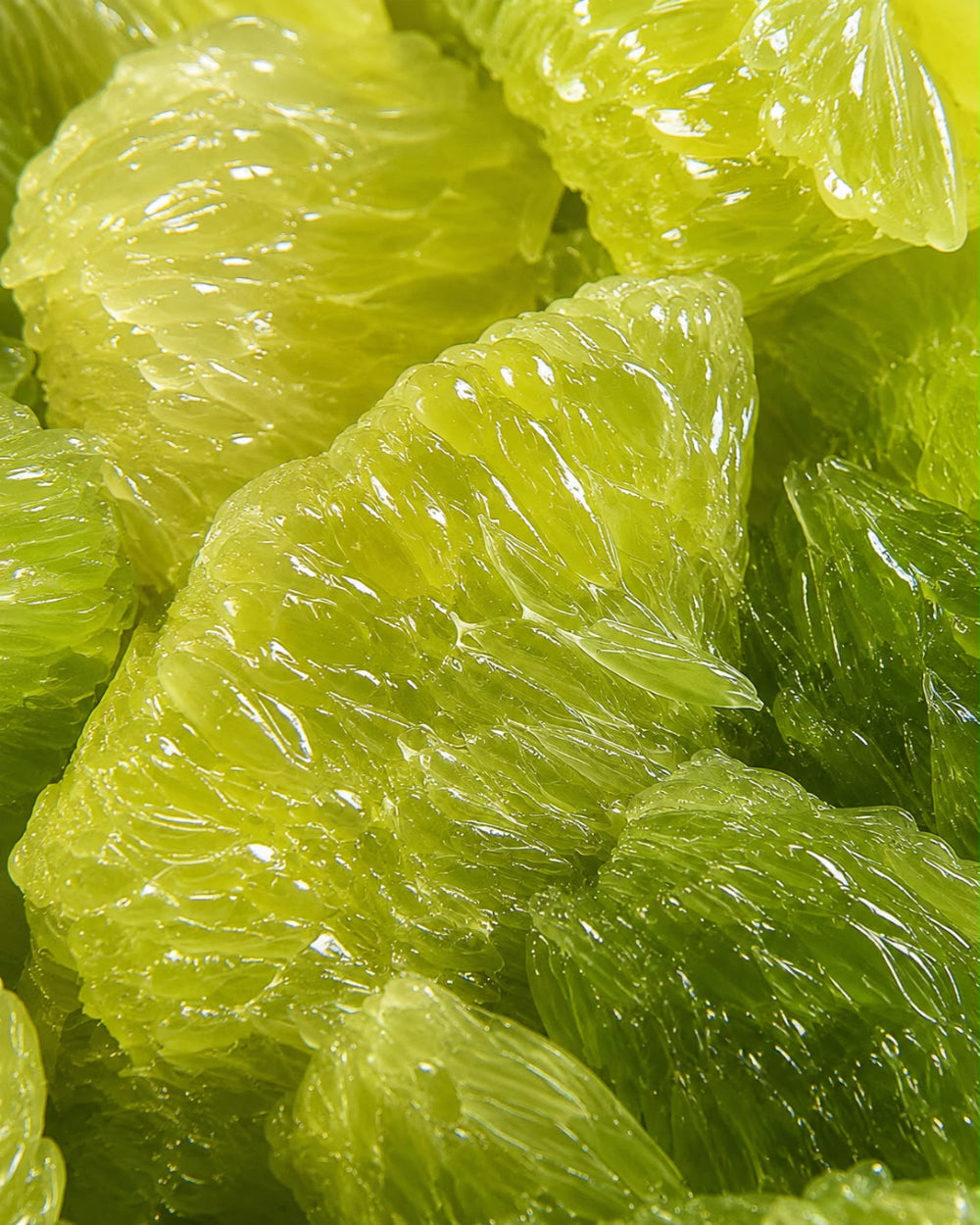 Close-up of translucent lime-green citrus segments with visible pulp and rind texture.