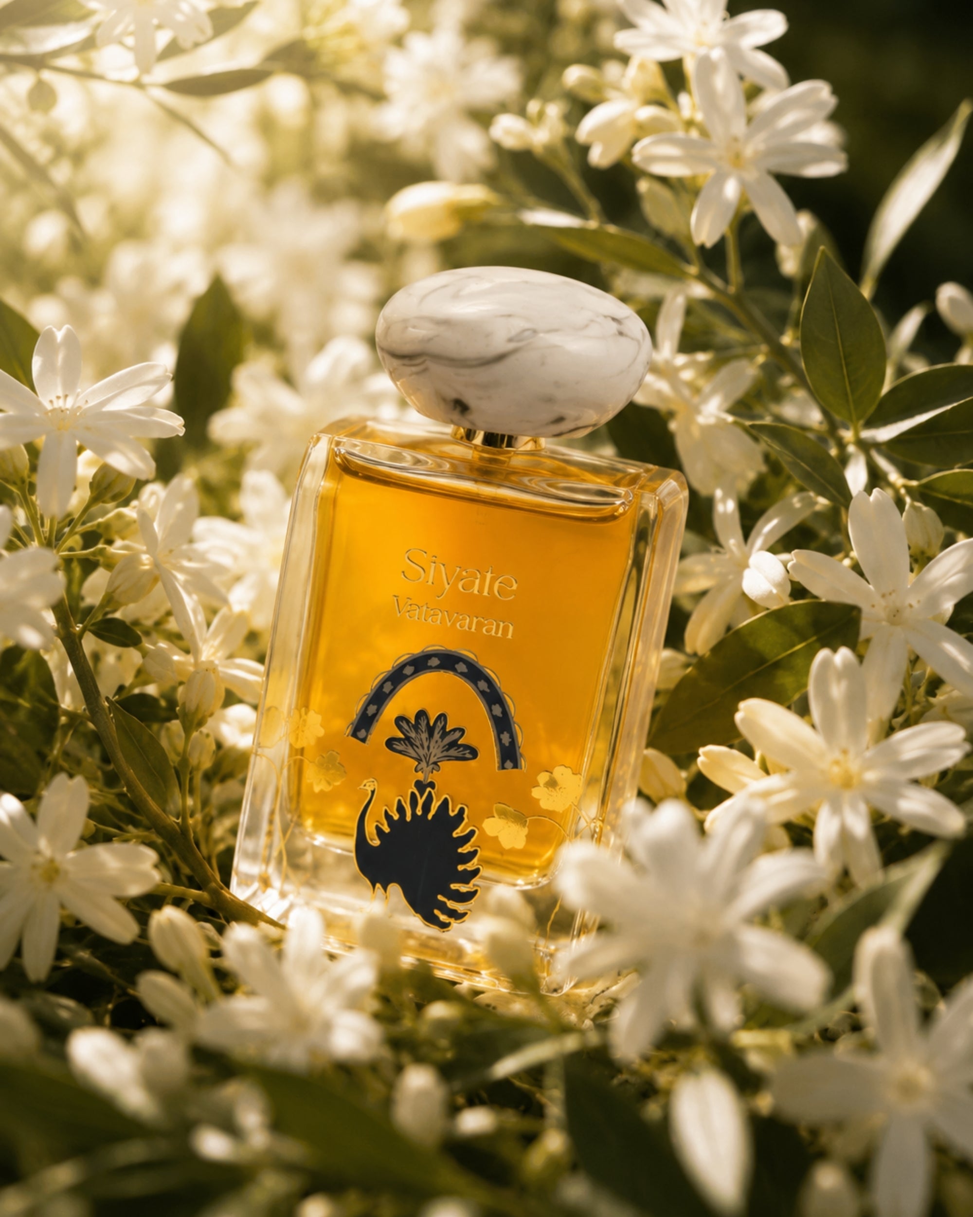 A rectangular glass perfume bottle filled with golden amber liquid, surrounded by white flowers and green leaves. The bottle has a white marbled cap and a black and blue graphic design on the front, with the text 'Sivule' and 'Savaran' visible.